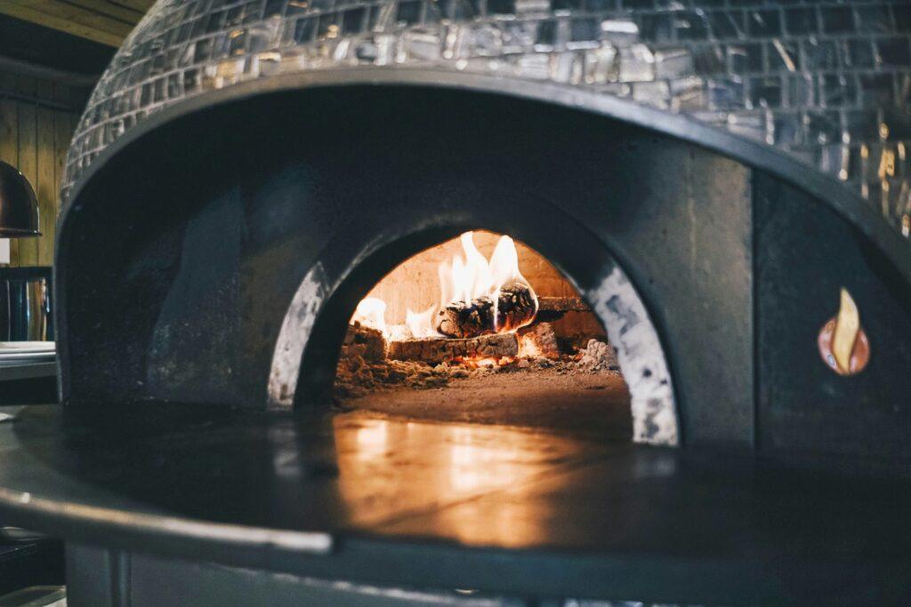 Moderner Pizzaofen mit Flammen und glühendem Holz im Inneren