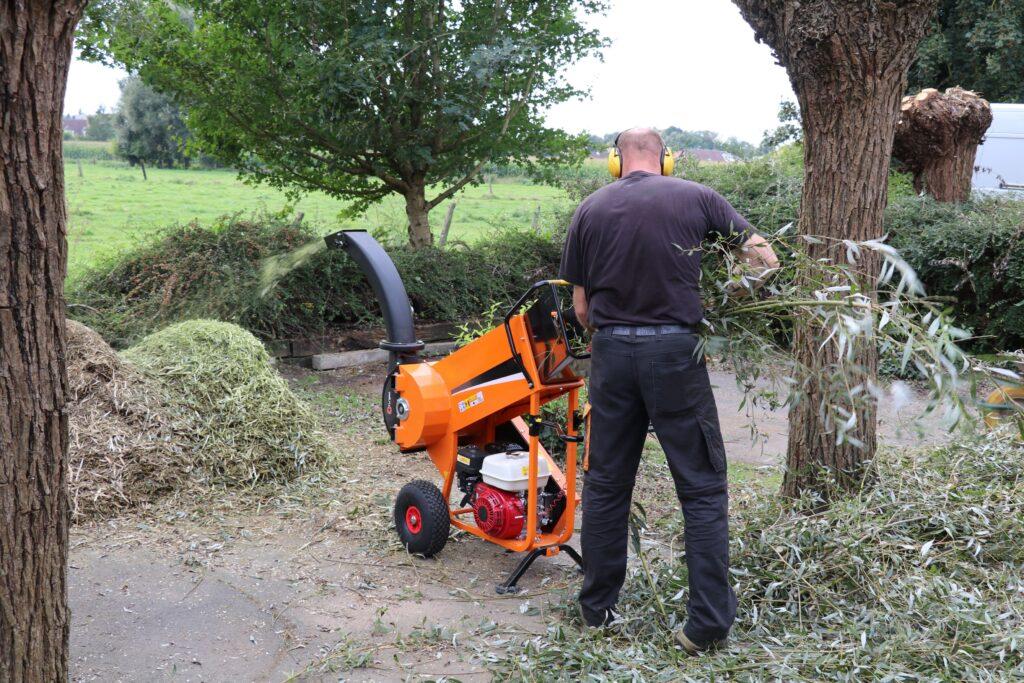 Person arbeitet mit leistungsstarkem Gartenhäcksler im Freien und verarbeitet frischen Astschnitt